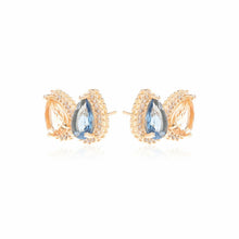 Cargar imagen en el visor de la galería, Pendiente Gotas cristal London Blue, cristal citrino y circonitas blancas, Chapado en oro de 18 quilates.
se puede hacer conjunto con el collar escapulario. Ventas separadas.
El pendiente en forma de lágrima es el accesorio perfecto para darle un toque especial a cualquier conjunto. El contraste entre el azul intenso del London Blue y el brillo dorado del Citrine crea un look sofisticado y con mucho estilo, mientras que la circonita cúbica blanca añade aún más brillo a la pieza. Elegante, moderno y con mu