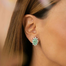 Cargar imagen en el visor de la galería, Este pendiente ovalado, con una fusión de esmeralda colombiana y circonita cúbica blanca, ofrece un look elegante y sofisticado en la medida justa. La piedra central realza el intenso verde con un brillo refinado, mientras que la circonita cúbica blanca ilumina la composición. Con un baño de rodio blanco, es una pieza moderna, delicada y encantadora.