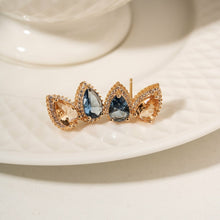 Cargar imagen en el visor de la galería, Pendiente Gotas cristal London Blue, cristal citrino y circonitas blancas, Chapado en oro de 18 quilates.

se puede hacer conjunto con el collar escapulario. Ventas separadas.

El pendiente en forma de lágrima es el accesorio perfecto para darle un toque especial a cualquier conjunto. El contraste entre el azul intenso del London Blue y el brillo dorado del Citrine crea un look sofisticado y con mucho estilo, mientras que la circonita cúbica blanca añade aún más brillo a la pieza. Elegante, moderno y con mu
